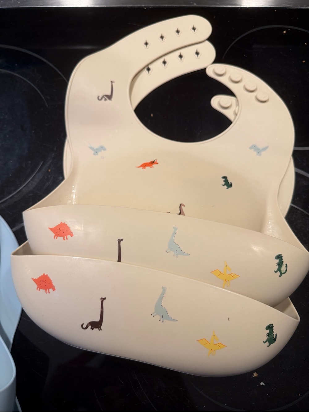 Mushie Silicone Dinosaur Bib with Catch-All Pocket - Cream